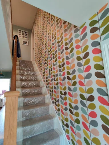 Stairwell wallpapered with a leaf pattern by Home Hues, stair treads protected during the hang