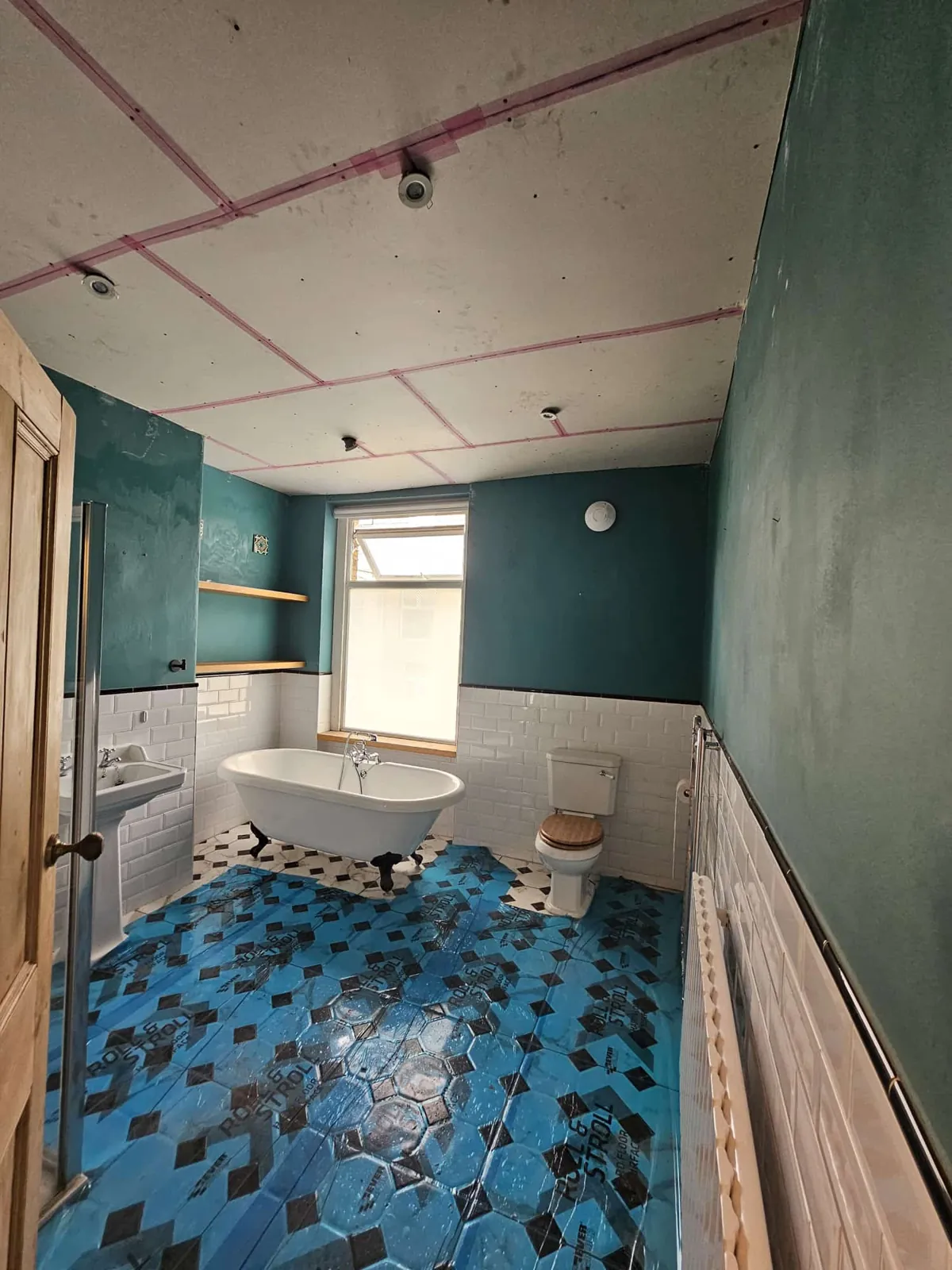 Scrim tape on every plasterboard joint across a bathroom ceiling, bath and floor protected
