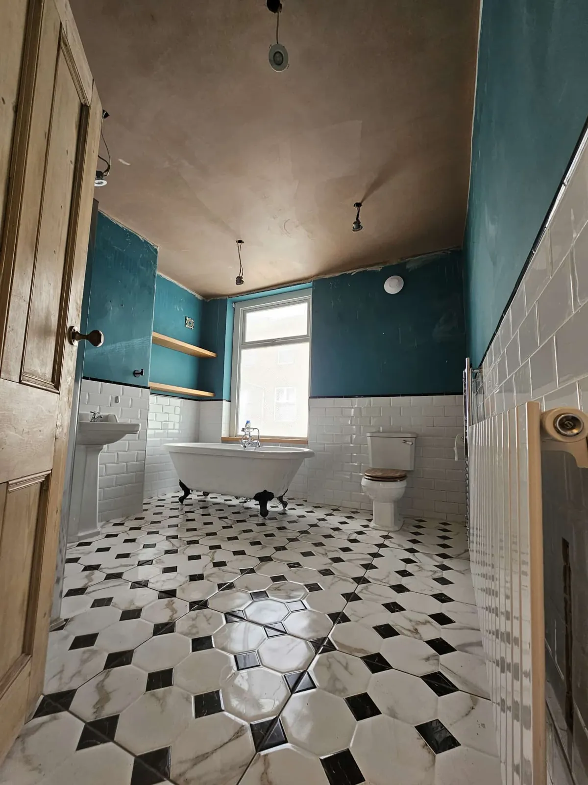 Victorian-style bathroom with a freshly skimmed ceiling drying above teal walls, white metro tiles and a roll-top bath