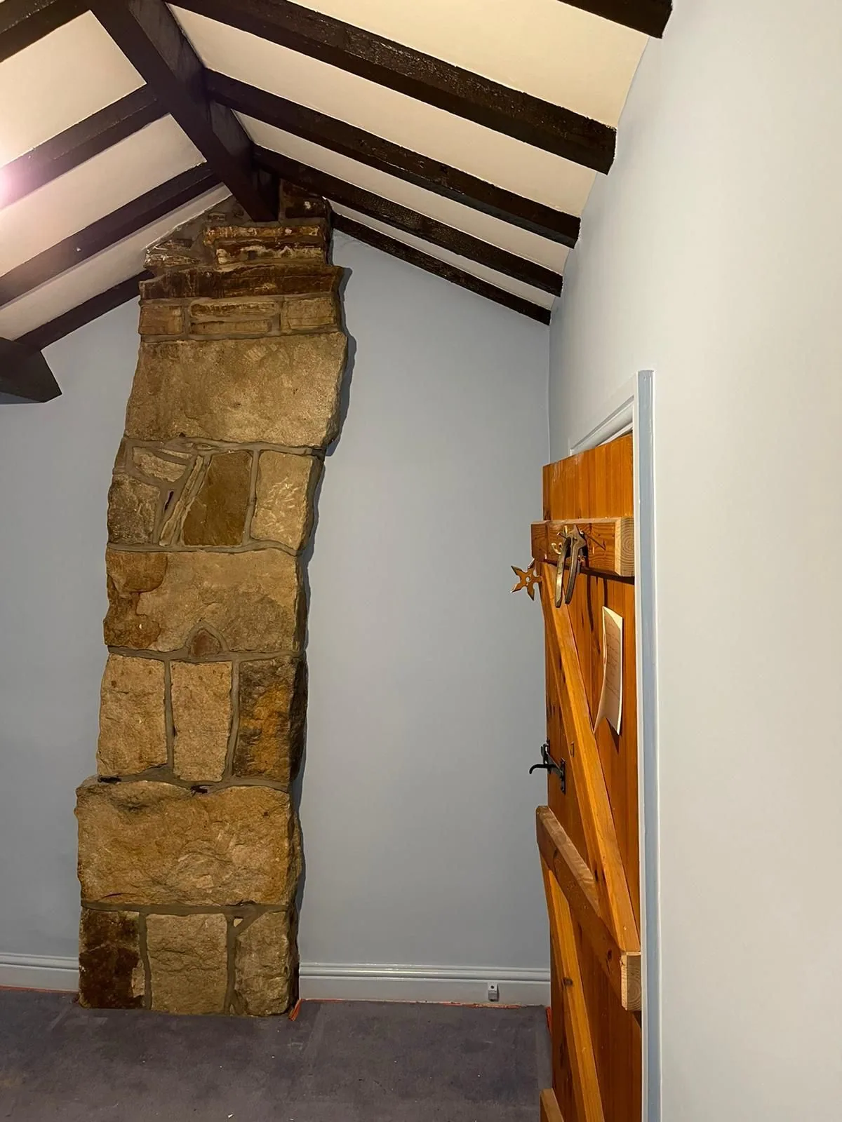 Exposed stone chimney column inside a freshly painted cottage bedroom