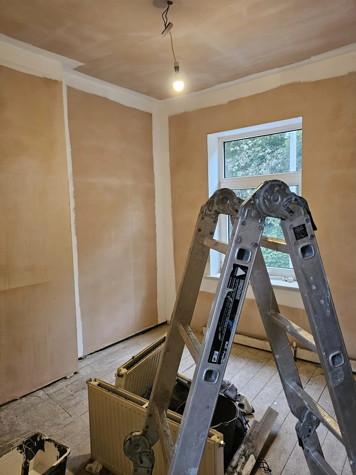 Bedroom in an older terrace freshly replastered in pink skim during a full Home Hues renovation, radiator off the wall