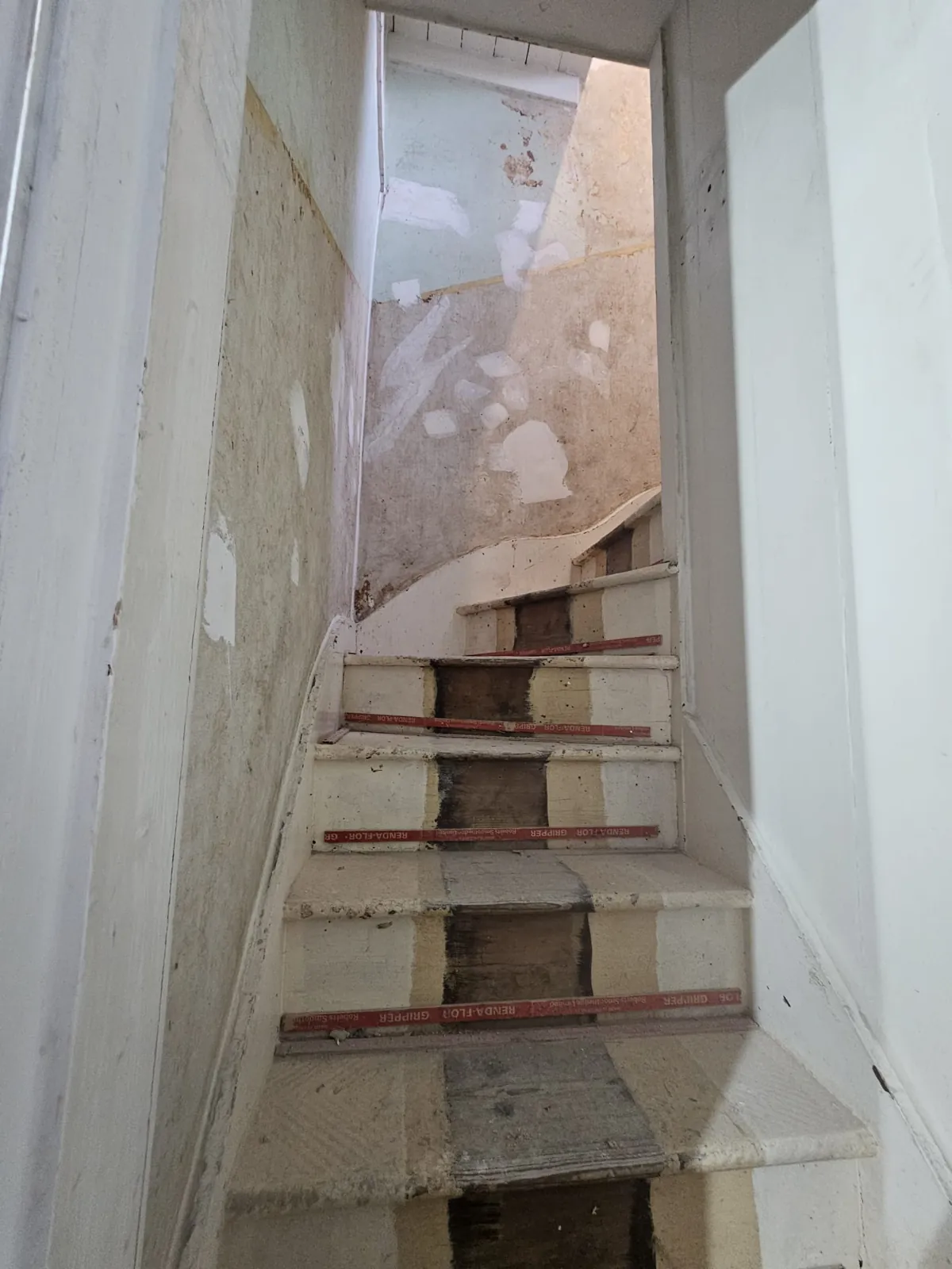 Narrow winding staircase with stairwell walls stripped and treads protected